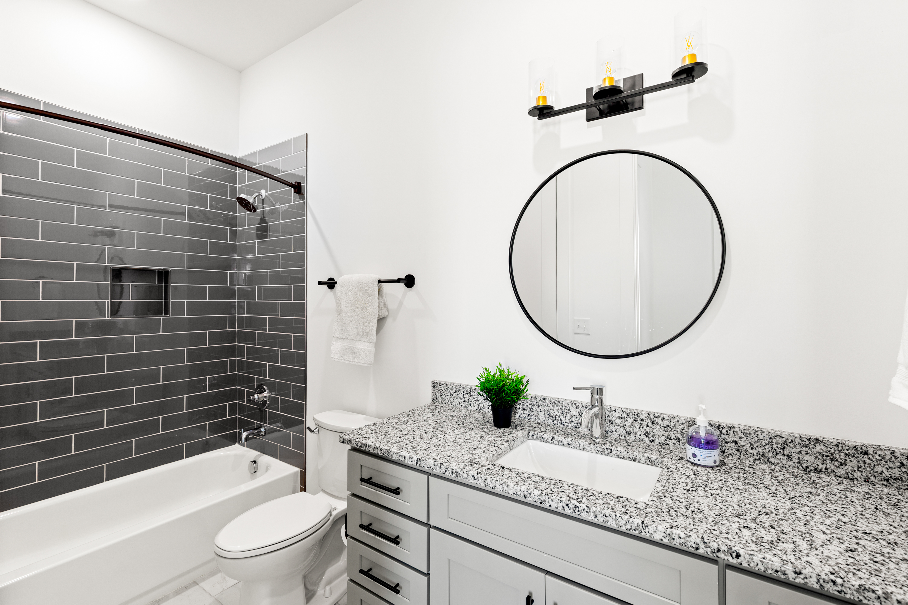 Elegant bathroom with black subway tile shower and granite vanity